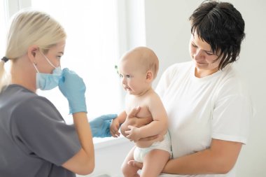 Çocuk doktoru küçük çocuğa aşı yapıyor.