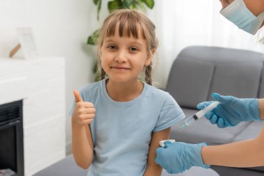 Küçük kız muayenehanedeki çocuk doktorundan aşı oluyor.