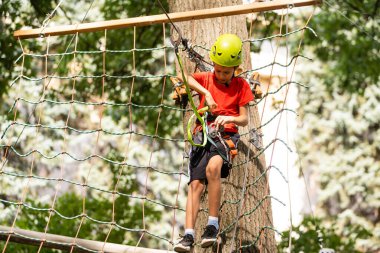 Çocuk tırmanışçı ip köprüde yürüyor,