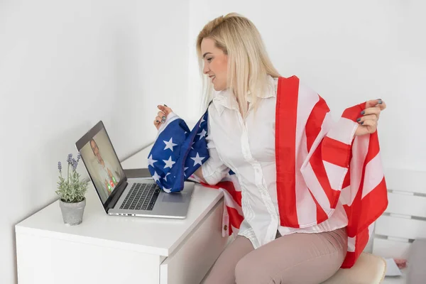 Amerikan bayrağı taşıyan kadın oturma odasında dizüstü bilgisayarda oturuyor.. — Stok fotoğraf