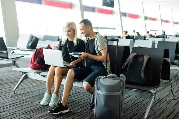 Concepto de viaje. Esperando el embarque. Feliz pareja amorosa en ropa casual en la terminal del aeropuerto con pasaporte con boletos. —  Fotos de Stock