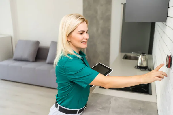 Egy nő megnyomja a gombot egy falra erősített ház termosztát digitális kijelző mutatja a hőmérsékletet. A koncepció imázs villanyszámla, fűtés, hűtés, környezetbarát, megtakarítás stb — Stock Fotó