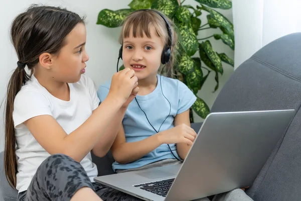 Due ragazze che lavorano sul computer portatile, sorridente e sorella maggiore aiutano i più giovani — Foto Stock