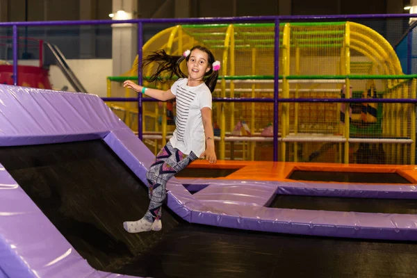 Çocukların oyun odasında, kapalı alanlarda oynayan ve trambolinde zıplayan küçük sevimli kız çocuğu portresi. Aktif kız spor merkezinde eğleniyor.. — Stok fotoğraf