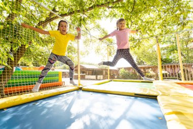 Trambolinle çömelmek için egzersiz yapan iki aktif genç kız.