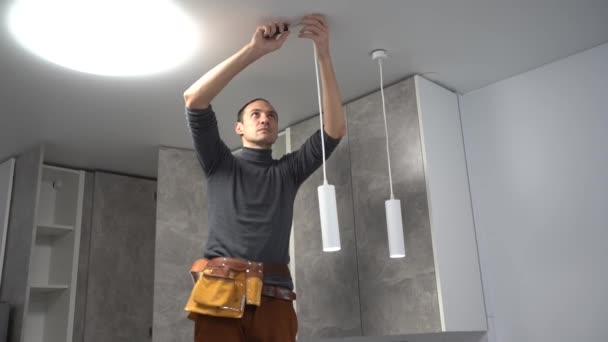 Elektricien in het huis na reparatie installeert een lamp — Stockvideo