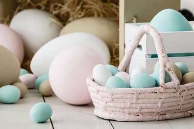 Paskalya kompozisyonu, tavşan ve beyaz tavuk yumurtaları hasır sepette, metin için arka plan boşluğunda