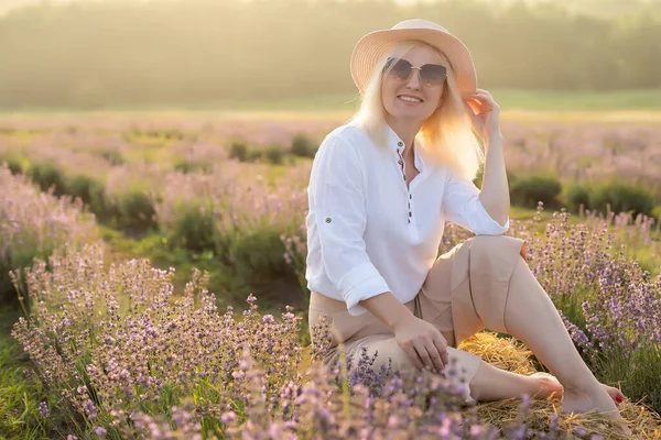若いブロンドの女性旅行者はラベンダーの花で囲まれたラベンダー畑でわら帽子をかぶって — ストック写真