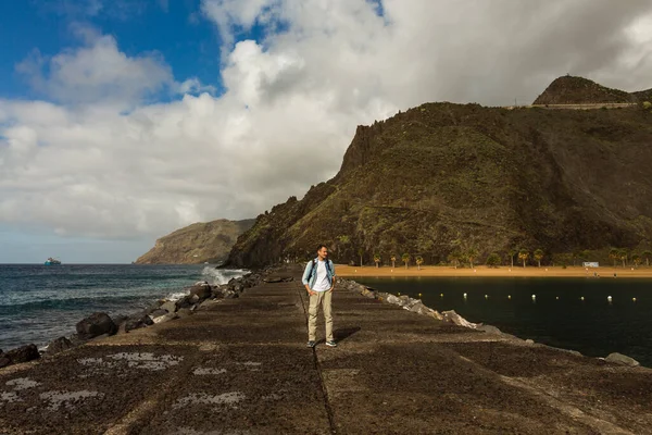 Hombre joven caucásico relajándose en la playa rocosa, viajero solo, destino de vacaciones en Tenerife, Islas Canarias, España — Foto de Stock