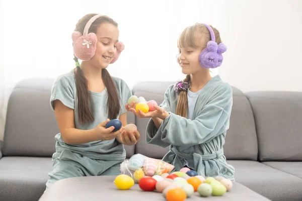 Zwei süße kleine Schwestern, die zu Ostern auf Eiersuche gehen. Entzückende Kinder feiern Ostern zu Hause. — Stockfoto