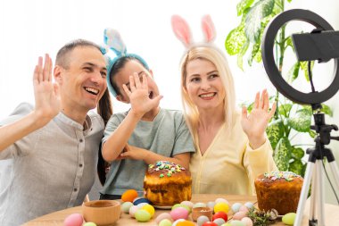 Aile, Paskalya tatilinde arkadaşlarıyla özel bir program kullanarak internet üzerinden iletişim kurar. İş arkadaşlarına tablet üzerinden video konferansı. Çiçekler ve renkli yumurtalarla süslenmiş bir masa.