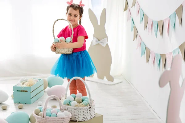 Симпатична маленька дівчинка з вухами кролика і кошиком великодніх яєць — стокове фото