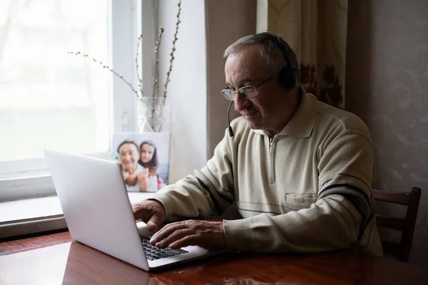 Evde dizüstü bilgisayar kullanan gözlüklü yaşlı adam. — Stok fotoğraf