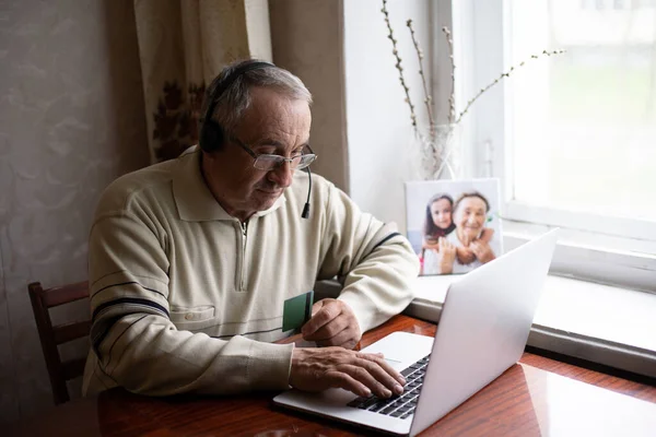 Elderly man with glasses using laptop at home — Stock Photo, Image