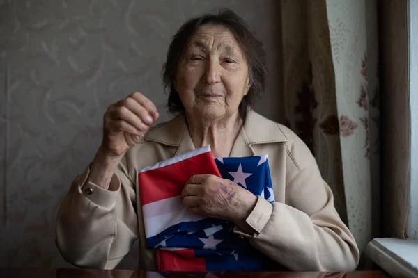 Старший, який пишається тим, що він американець, дуже стара жінка з американським прапором.. — стокове фото