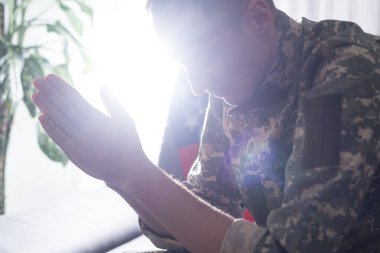 Üzgün asker üniformalı kanepede otururken ağzını kapsayan