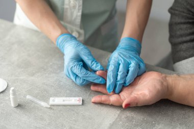 Kadın doktorlar beyaz önlük ve tıbbi eldiven giyip hastanedeki hematoloji laboratuvarında test tüpü tutuyorlar.