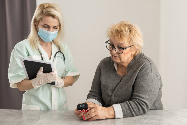 врач поговорит со старой пациенткой о симптомах болезни, врач использует пульсометр кончика пальца со старым пациентом, проверка здоровья пожилых людей и обследование здоровья, медицинские технологии