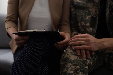 Psikologla terapi seansı sırasında koltukta oturan depresif bir asker.