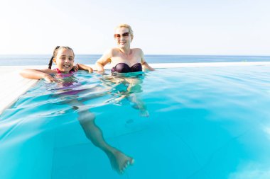 gülümseyen güzel kadın smear için güneş yanığı kremi ile aquapark havuzu yakınlarında küçük bir kız