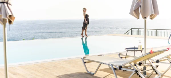 Atrakcyjna młoda kobieta stoi przy basenie z panoramicznym widokiem. — Zdjęcie stockowe
