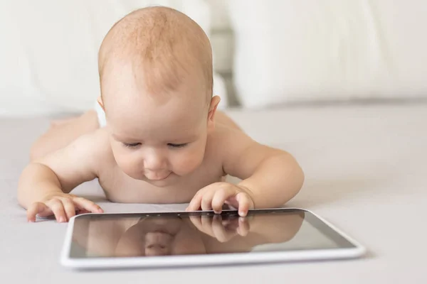 Een baby van zes maanden met een tablet computer, naar het scherm kijkend, thuis — Stockfoto