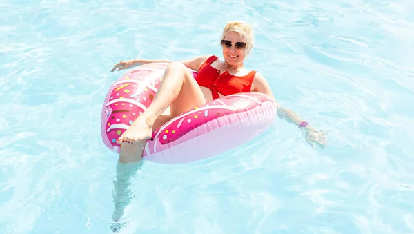 Vrouw ontspannen op donut lilo in het zwembad bij prive-villa. Opblaasbare ring en matras. Zomervakantie idyllisch. Hoog zicht van boven — Stockfoto
