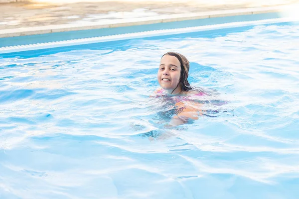 खुश छोटी लड़की तैराकी सूट में पूल में मज़ा कर रही है . — स्टॉक फ़ोटो, इमेज
