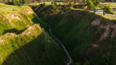 Manzara: dağlar, göl, vadi, ağaçlar ve patika.