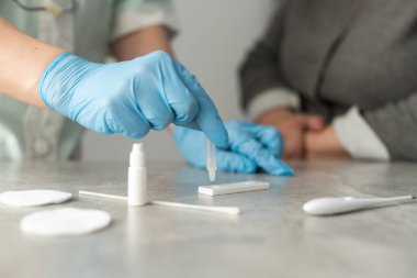 Kadın doktorlar beyaz önlük ve tıbbi eldiven giyip hastanedeki hematoloji laboratuvarında test tüpü tutuyorlar.