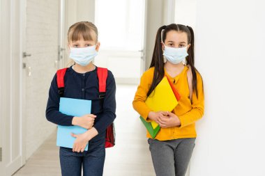 Sırt çantalı koruyucu maskeli iki öğrenci arkadaş. Okul konseptinde gün
