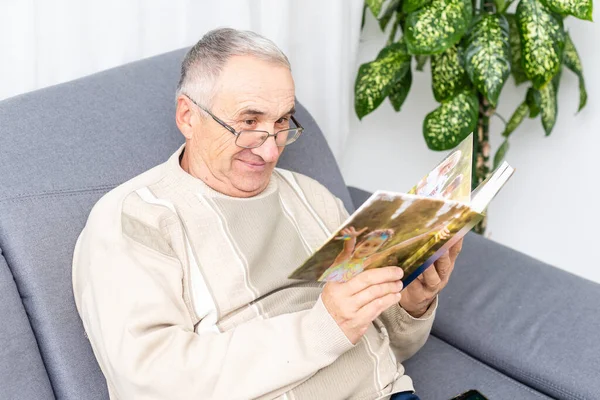 Un vieil homme dans une salle d'hôpital regardant un photobook — Photo