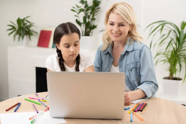 Bella giovane donna e la sua piccola figlia carina stanno usando il computer portatile a casa. Godere di trascorrere del tempo insieme. — Foto Stock