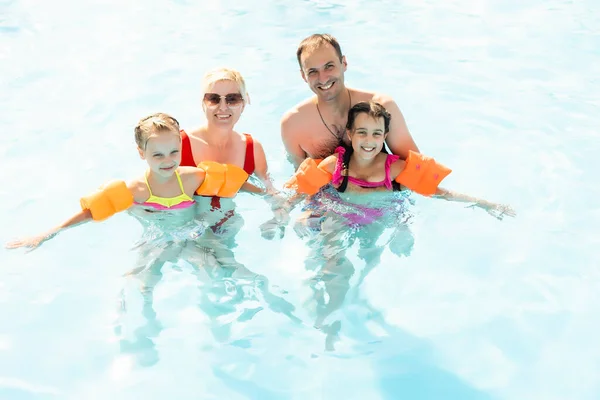 Glückliche Familie spielt im Schwimmbad. Sommerferienkonzept — Stockfoto