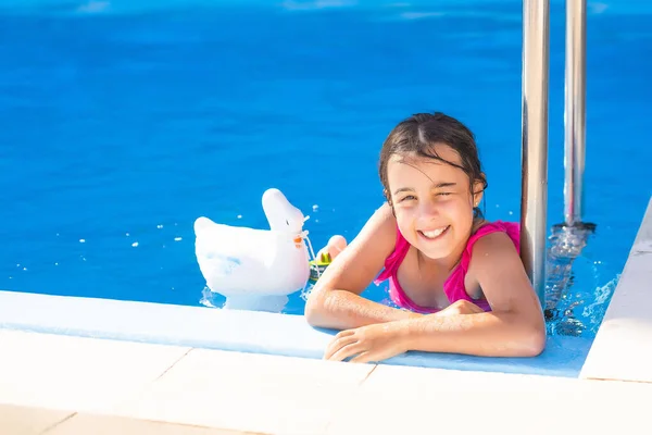 Šťastná holčička baví v bazénu v plavkách. — Stock fotografie