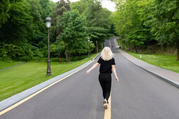 Attraktiv ung kvinna promenader längs vägen njuter av naturen. — Stockfoto