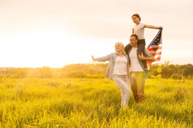 Vatansever bayram. Mutlu aile, ebeveynler ve kızlar Amerikan bayrağı taşıyan çocuklar. ABD 4 Temmuz 'u kutladı.