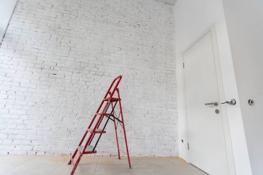 Apartmanda tamirat var. Duvarları yeni boyanmış parlak bir odanın içinde keçi boyacıları inşa ediyorlar. İnşaat evindeki beyaz duvarlar.