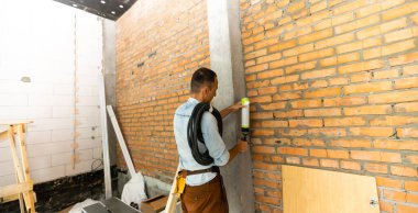 Alet kemeri takan tamirci binada duruyor, ofiste tadilat yapıyor.