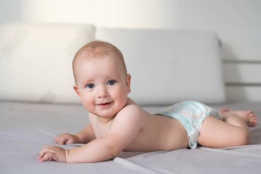 Gri bir kanepede gülümseyen şirin bir bebek.