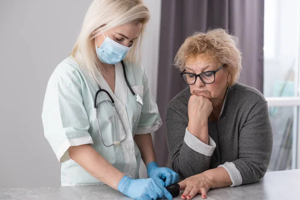 Κοντινή φωτογραφία με γυναικεία χέρια. Γυναίκα γιατρός μετρά τους ασθενείς παλμό και κορεσμό οξυγόνου σε μεσήλικες γυναίκα χρησιμοποιώντας ένα παλμικό οξύμετρο, έννοια υγειονομικής περίθαλψης. — Φωτογραφία Αρχείου