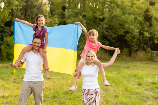 Família feliz s com bandeira da Ucrânia no campo. — Fotografia de Stock