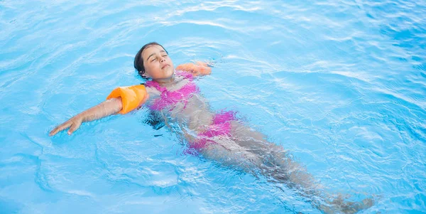 Jolie petite fille nageant dans la piscine extérieure et s'amuser — Photo