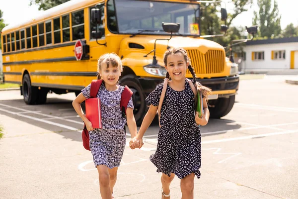 Raparigas alegres ao lado do autocarro escolar. Para trás. Voltar ao conceito de escola. — Fotografia de Stock