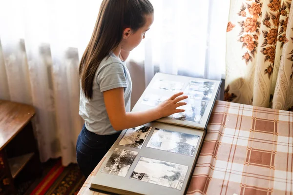 Söt tjej som bläddrar i ett familjealbum. Vintage stil — Stockfoto