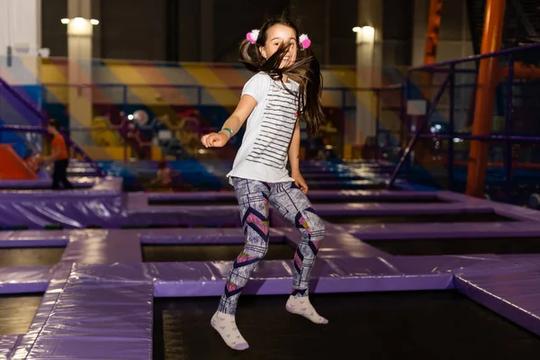 Criança a saltar ao trampolim no parque infantil. Menina criança ativa se divertindo no centro esportivo . — Fotografia de Stock