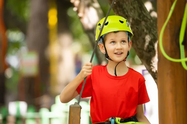 Lindo chico de escuela disfrutando de un día soleado en un parque de actividades de aventura de escalada — Foto de Stock