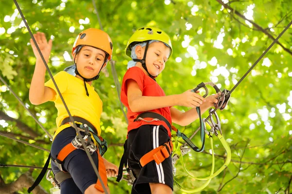 森林探险公园里的孩子孩子们爬上高绳的小径.敏捷性和攀爬户外儿童娱乐中心.小女孩在外面玩。有绳索的学校操场. — 图库照片