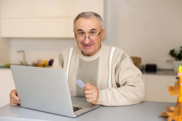 Sağlıklı, beyaz saçlı yaşlı Asyalı bir adamın bilgisayar laptopu ve kredi kartıyla ev konseptinde internet üzerinden alışveriş yapması ve ödemesini yapması mutluluktur.. — Stok fotoğraf