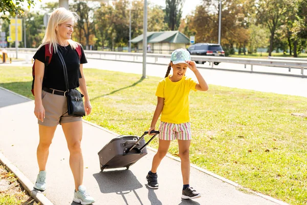 Matka i córeczka jadą z walizkami na lotnisko. turystyka i podróże. — Zdjęcie stockowe